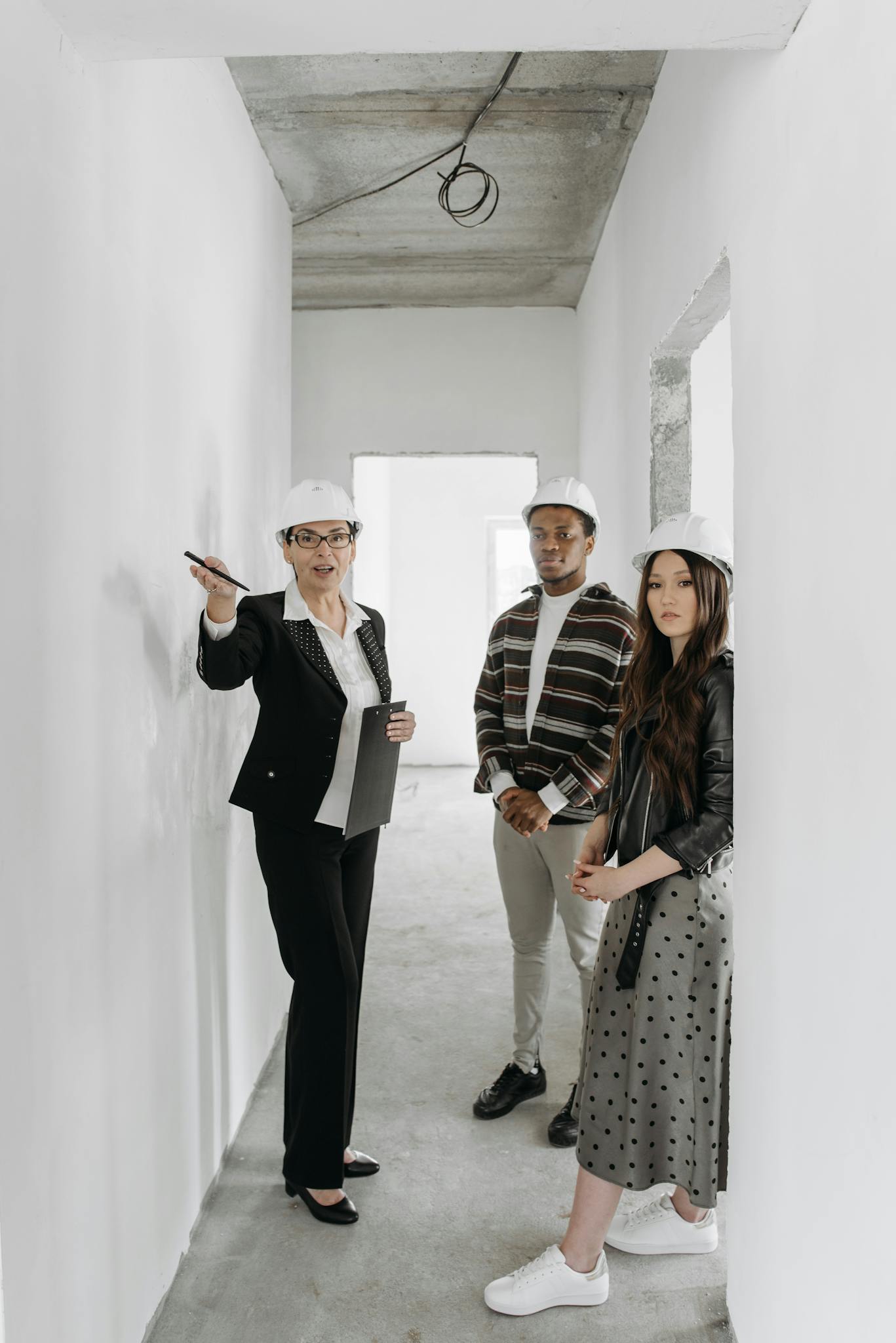 A diverse group of adults in hard hats touring a building site with a realtor.