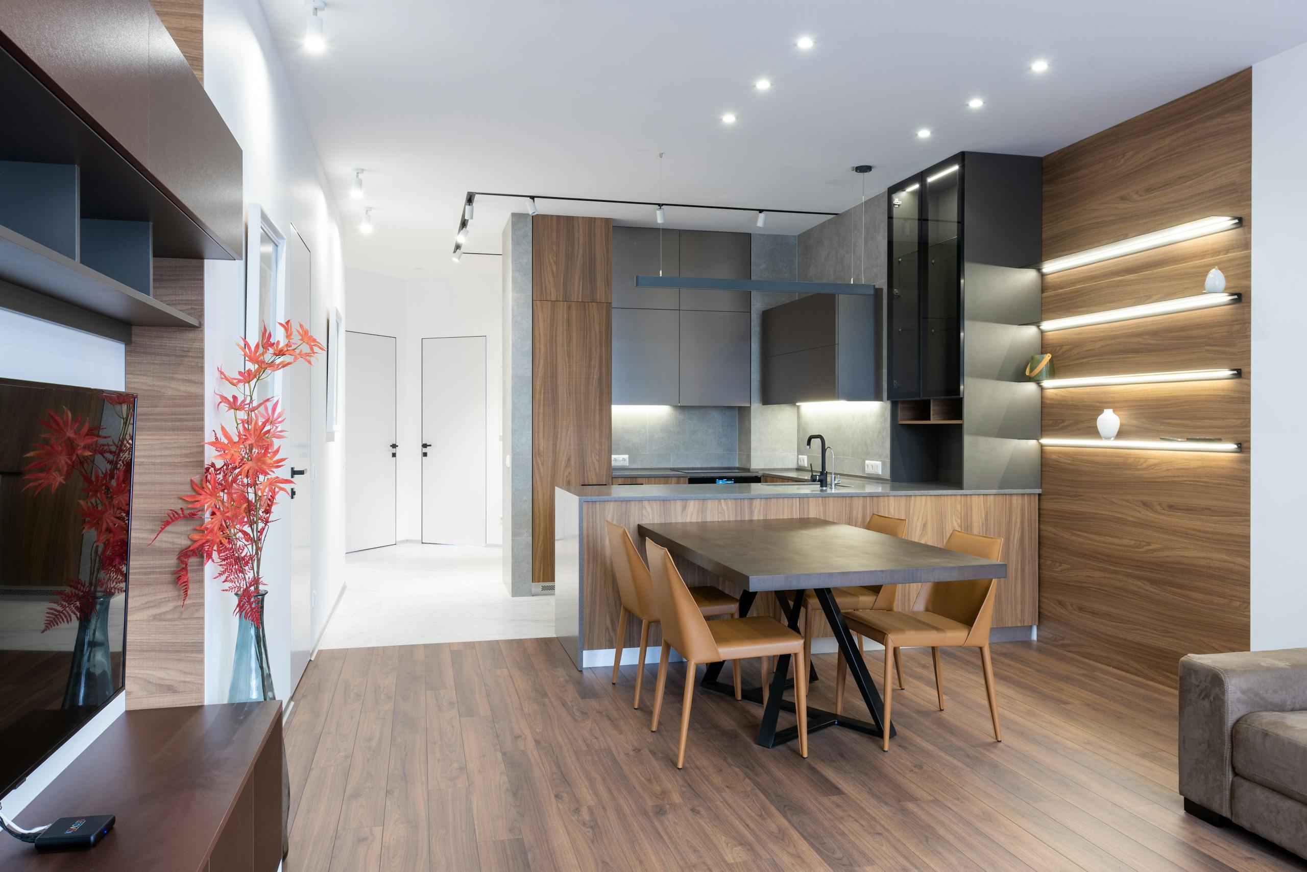 Interior of modern apartment with TV set near table and chairs placed at kitchen counter with contemporary kitchenware at home